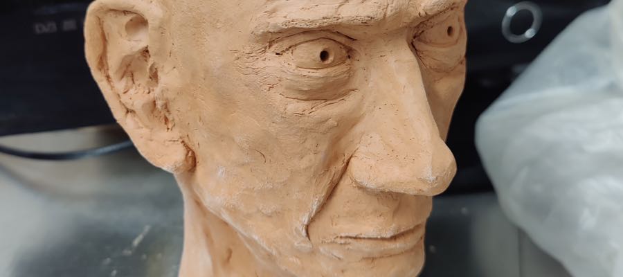 A clay sculpture profile of an older man with a mohawk hairstyle