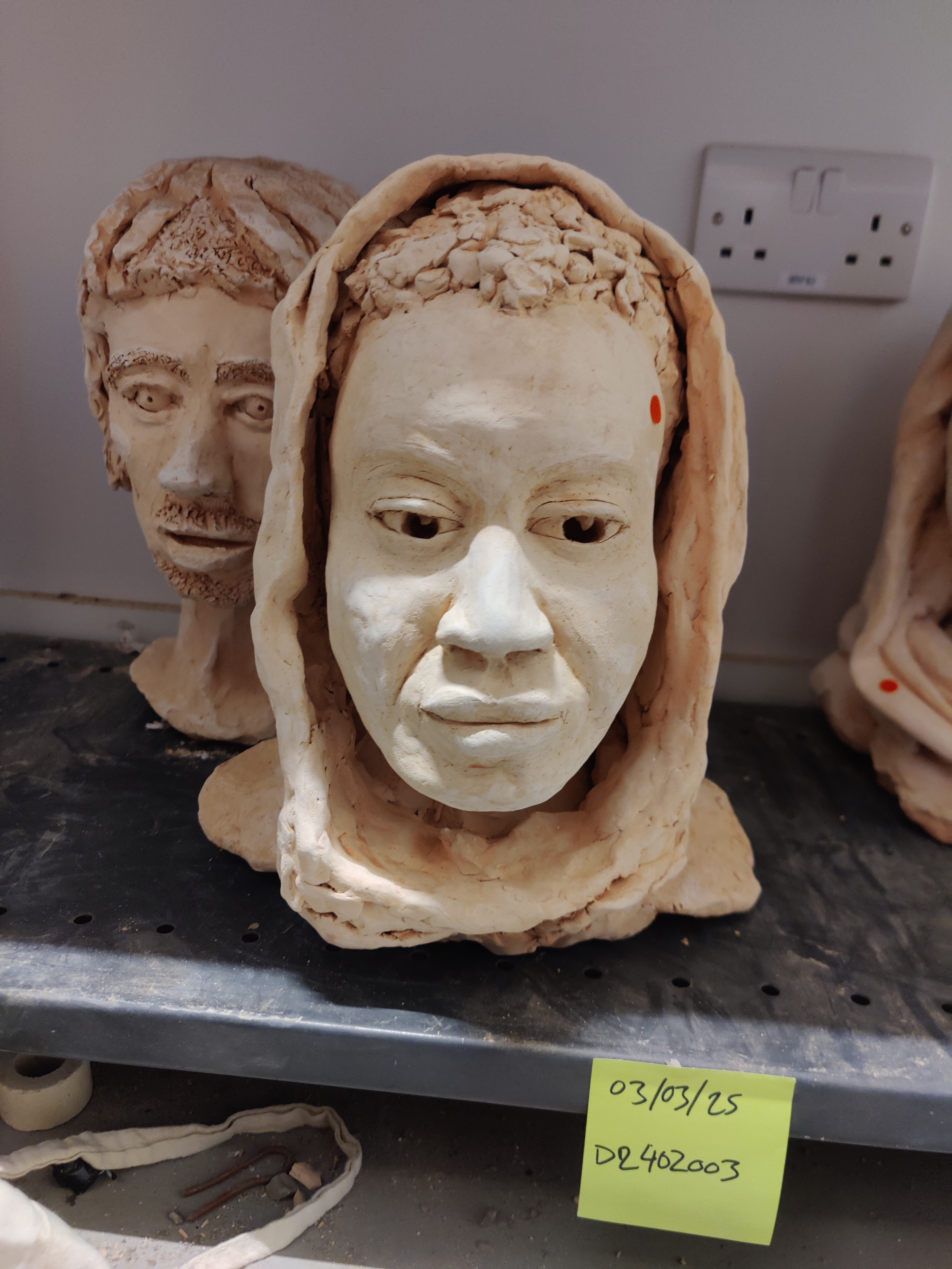 Bisque fired bust sitting on a drying shelf in the kiln room