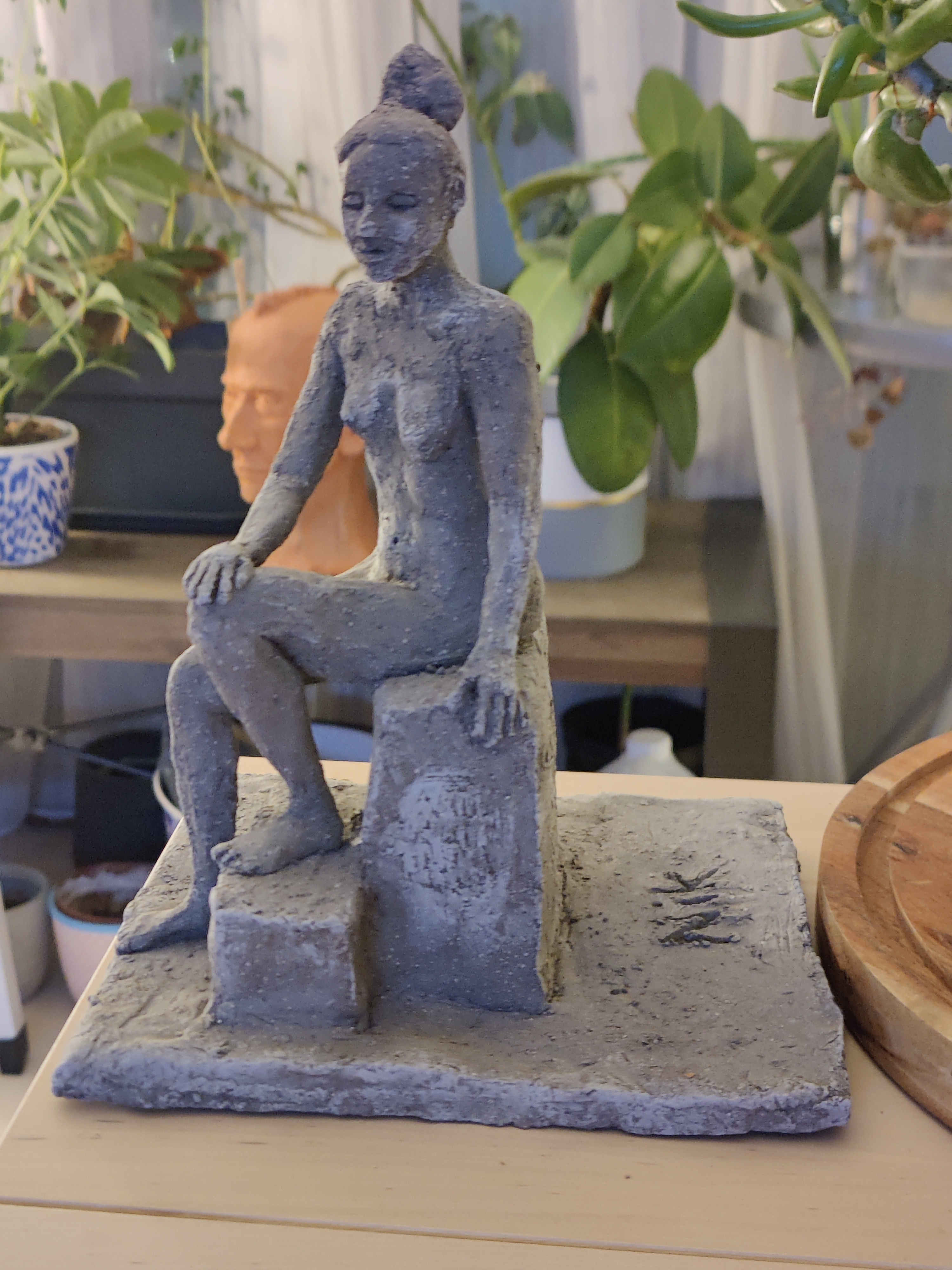 Fired clay model of a nude woman sitting on a block