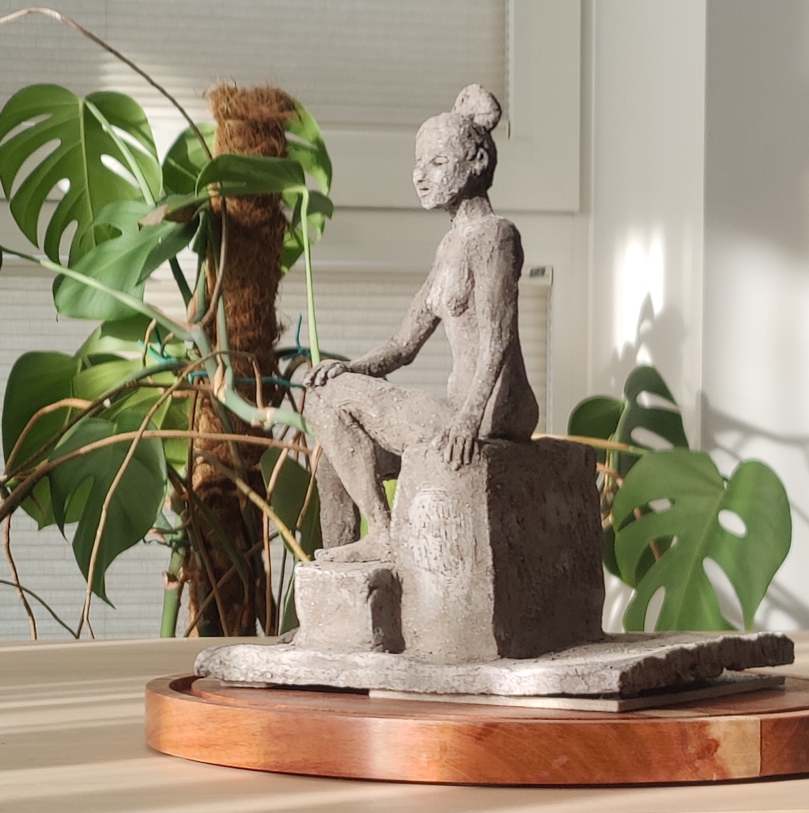 Fired clay model of a nude woman sitting on a block